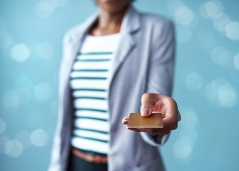 Credit card in the hands of a finance business woman paying, buying and making a purchase while standing against a blue studio background alone. Corporate professional giving a debit card for payment