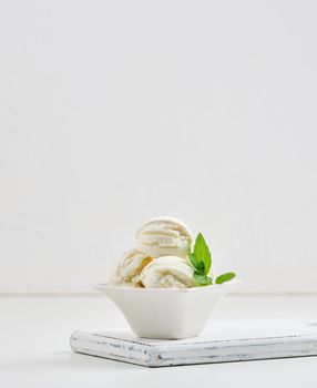 Vanilla ice cream balls with green mint leaf in a white ceramic plate