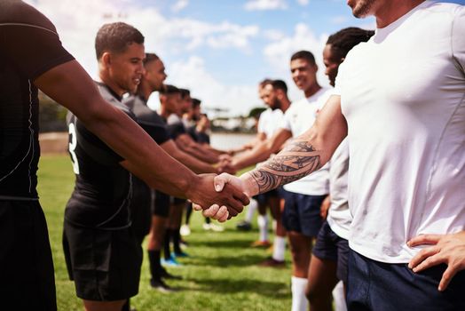 Play well, play fair. a group of young rugby players shaking hands on the field.