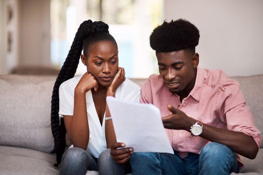 How are we going to afford this. a young couple looking stressed while going over paperwork at home.