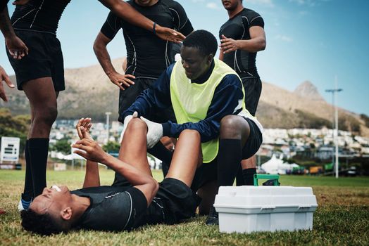 This looks like a bad injury. a young rugby player receiving first aid assistance on the field.