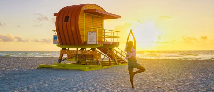 Asian women doing yoga during sunrise on the beach at Miami Florida South Beach