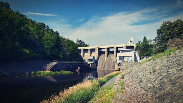 A dam on the Brno Reservoir by the Svratka River with a small power plant. Beautiful sunny summer day in nature.