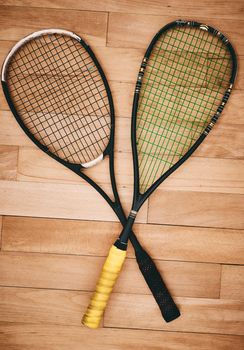A good quality racket makes for a good game. two squash racquets on the floor of a squash court.