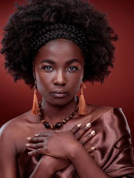 African Beauty personified. Cropped portrait of a beautiful young woman posing against a red background.