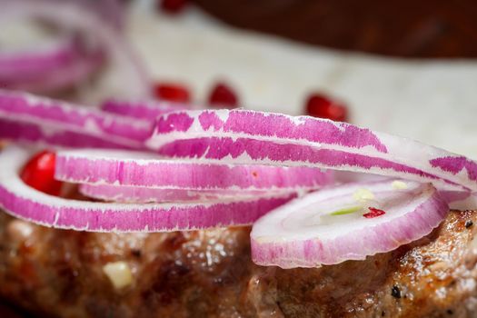 A dish cooked on the kebab grill. Georgian dishes. Garnished with onions and pomegranate seeds
