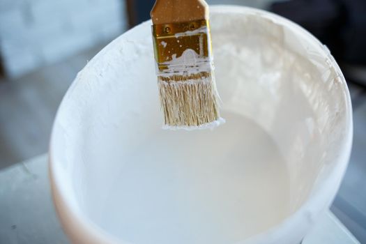 Paint brush in a bucket with white paint