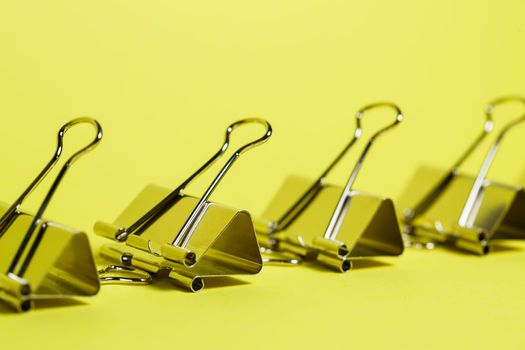Metal binders on a yellow background. Stationery accessories. Paper clip
