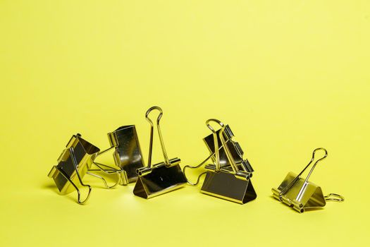 Metal binders on a yellow background. Stationery accessories. Paper clip