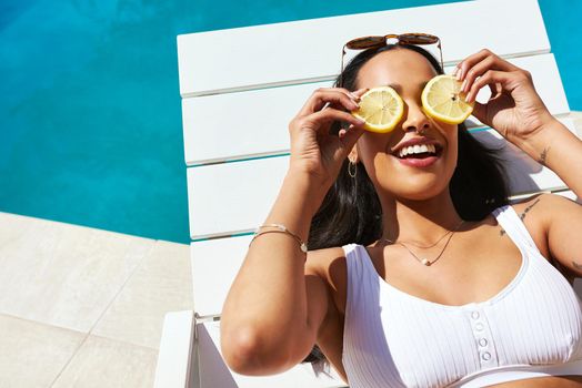 When life hands you lemons, put it to good use. a young woman posing with lemon slices over her eyes by the poolside.