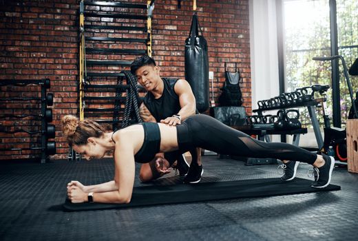 Youll never regret getting a personal trainer. a young woman working out with her personal trainer.