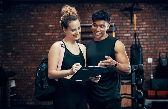 Sign up for our new fitness program. a sporty young woman talking to a fitness trainer at the gym.