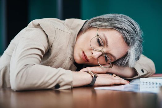 A short nap wont hurt anyone. an attractive mature businesswoman asleep at her desk in her home office.