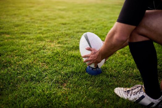 Working on my skill. an unrecognizable sportsman crouching alone during rugby practice in a sports club.