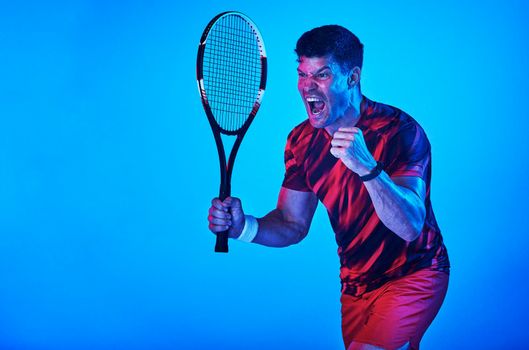I love this sport. Blue filtered shot of a man posing with a tennis racket in the studio.
