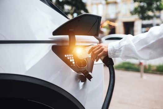 Human hand is holding Electric Car Charging nozzle.