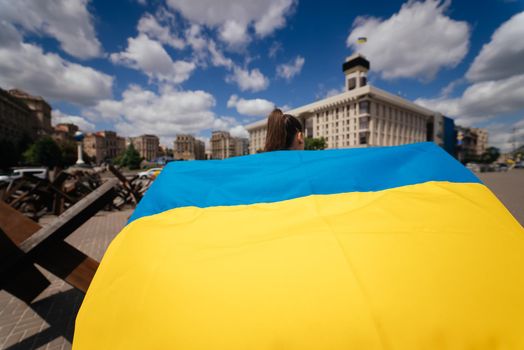 Young woman carries the flag of Ukraine fluttering behind her