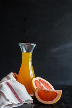 Organic fresh grapefruit juice in vintage bottle with ruits on dark wooden table