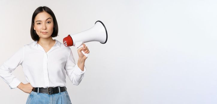 Image of modern asian woman with megaphone, making announcement, white background