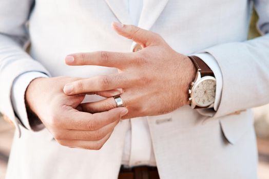 This wedding ring is a symbol of a lifetime commitment. an unrecognizable bridegroom adjusting his ring on his wedding day.