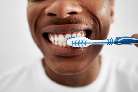 The more you brush, the longer your teeth will stay healthy. a young man brushing his teeth in the bathroom at home.