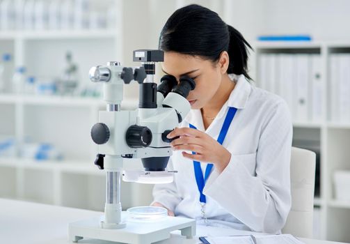 Medical research done right. a young scientist using a microscope in a laboratory.