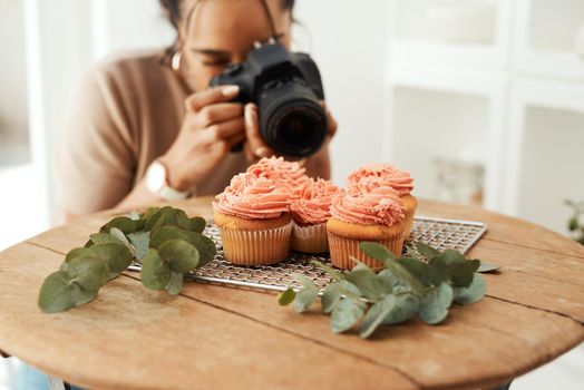 Making sure I get the right angle. an attractive young businesswoman using her camera to photograph cupcakes for her blog.
