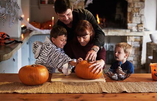 Our family loves celebrating halloween. an adorable young family carving out pumpkins and celebrating halloween together at home.