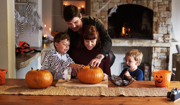 Things are getting really spooky right now. an adorable young family carving out pumpkins and celebrating halloween together at home.