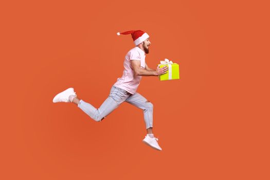 Man jumping in air or running quickly fast to give present box for Christmas, expressing happiness.