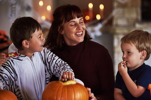Mommys little monsters. two adorable little boys carving out pumpkins and celebrating halloween with their mother at home.