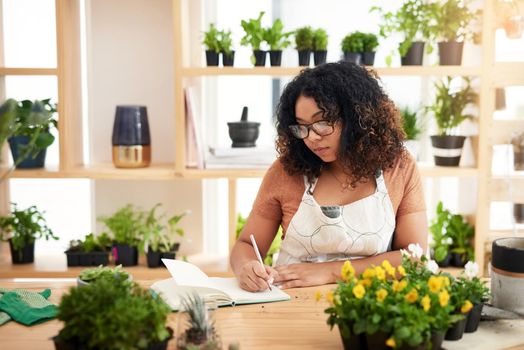 She takes are botany seriously. an attractive young female botanist making notes while working in her florist.