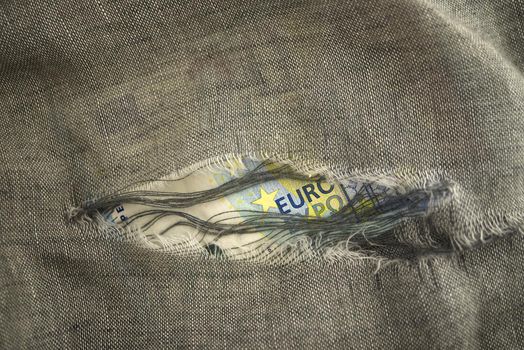 Euro banknote viewed through torn fabric