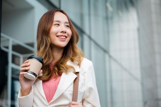 businesswoman holding coffee cup takeaway going to work she walking near her office building