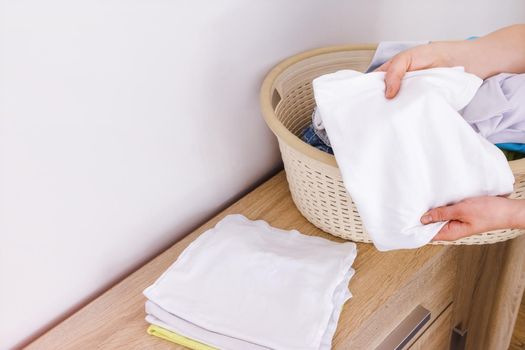 Close-up of a white t-shirt in hands of a woman. Laundry concept, washing powder