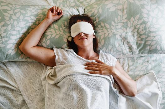 I dont want to get out of bed today. an attractive young woman sleeping with a sleep mask on in her bed at home.