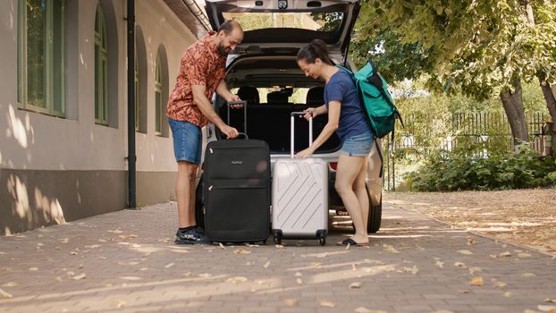Couple loading vehicle trunk with luggage
