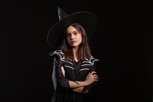 Little witch with a black dress looking at the camera with a serious expression