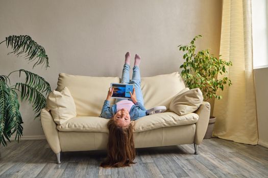 little girl lying upside down on sofa