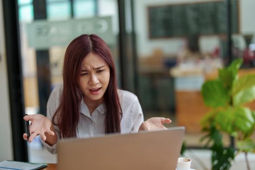 Asian female employees use computers to communicate with partners.