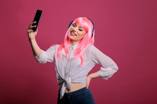 Young adult with pink hair taking pictures or recording video
