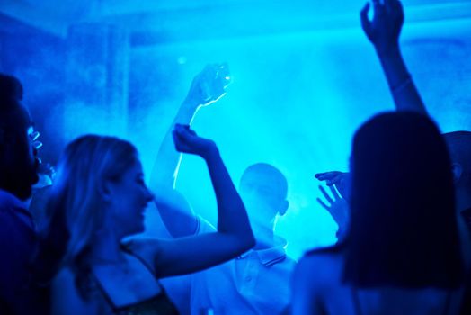 Let the music take over. a crowd of people dancing inside of a club at night.