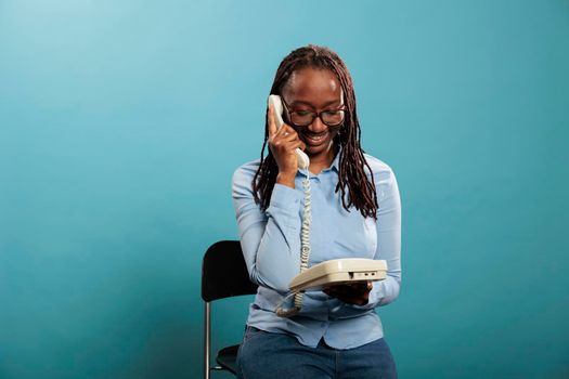 Happy smiling landline telephone operator having a conversation on wired phone on blue background.