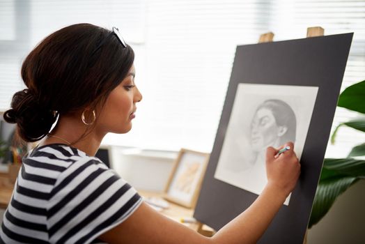 Attention to detail is the secret. an attractive young artist drawing a portrait of a woman inside her studio.