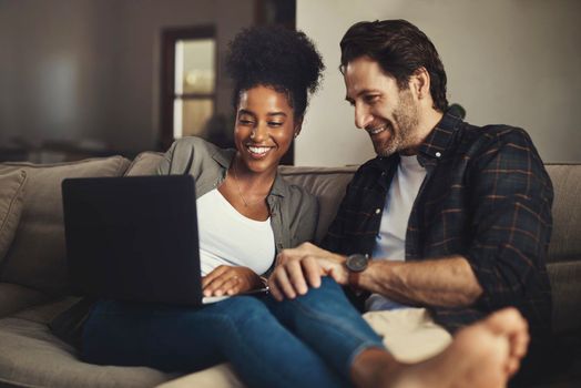 She always chooses the best movie. a happy young couple using a laptop while relaxing on a couch in their living room at home.