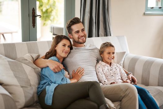 First rule of the weekend Spend time with family. a happy young family relaxing on the sofa and watching tv together at home.