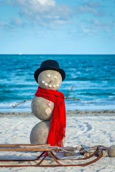 Snowman with red scarf, Hat and sled on the Miami Beach, Florida