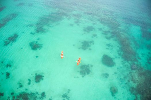 The ocean called, we answered. High angle shot of two adventurous young couples canoeing together in the beautiful oceans of Indonesia.