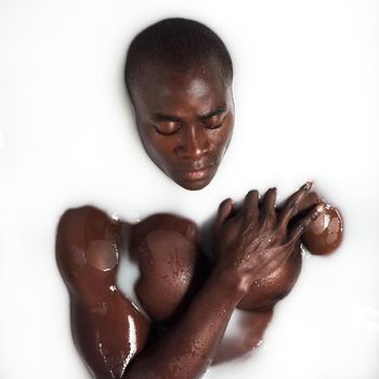 Real men take milk baths. a muscular young man having a milky bath at home.