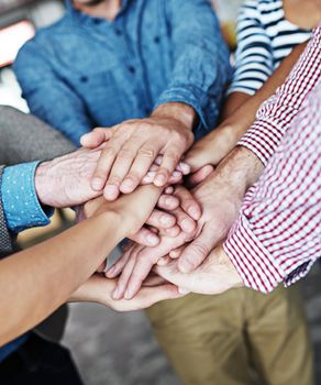 Diverse business people stack hands together showing support, teamwork and motivation or success for a project in the office. Group of colleagues cooperate and celebrate success after a meeting